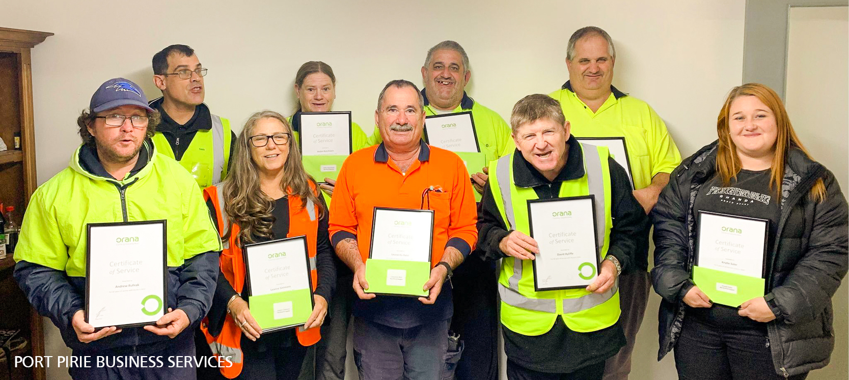 Port Pirie staff and employees celebrating their service awards. 9 people standing and smiling with their certificates. 