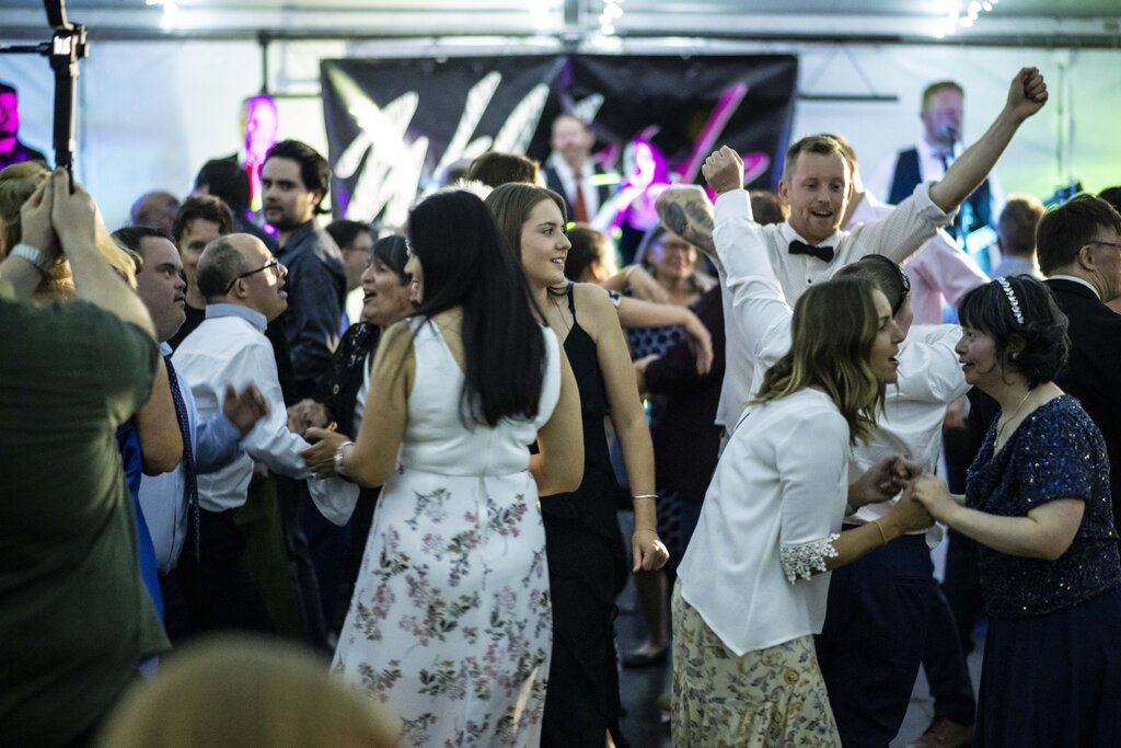 Dance floor filled with people dancing with a band blurred in the far background