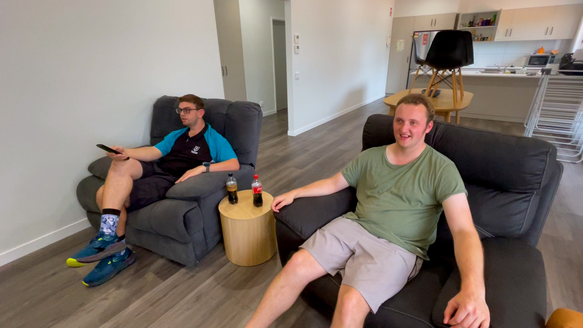 Two friends sit on lounge chairs watching tv