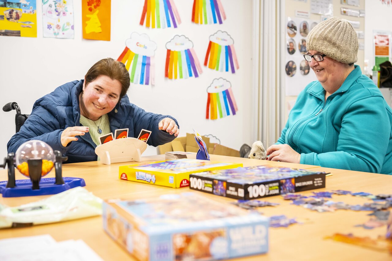 Two women sit at a table playing Uno with each other