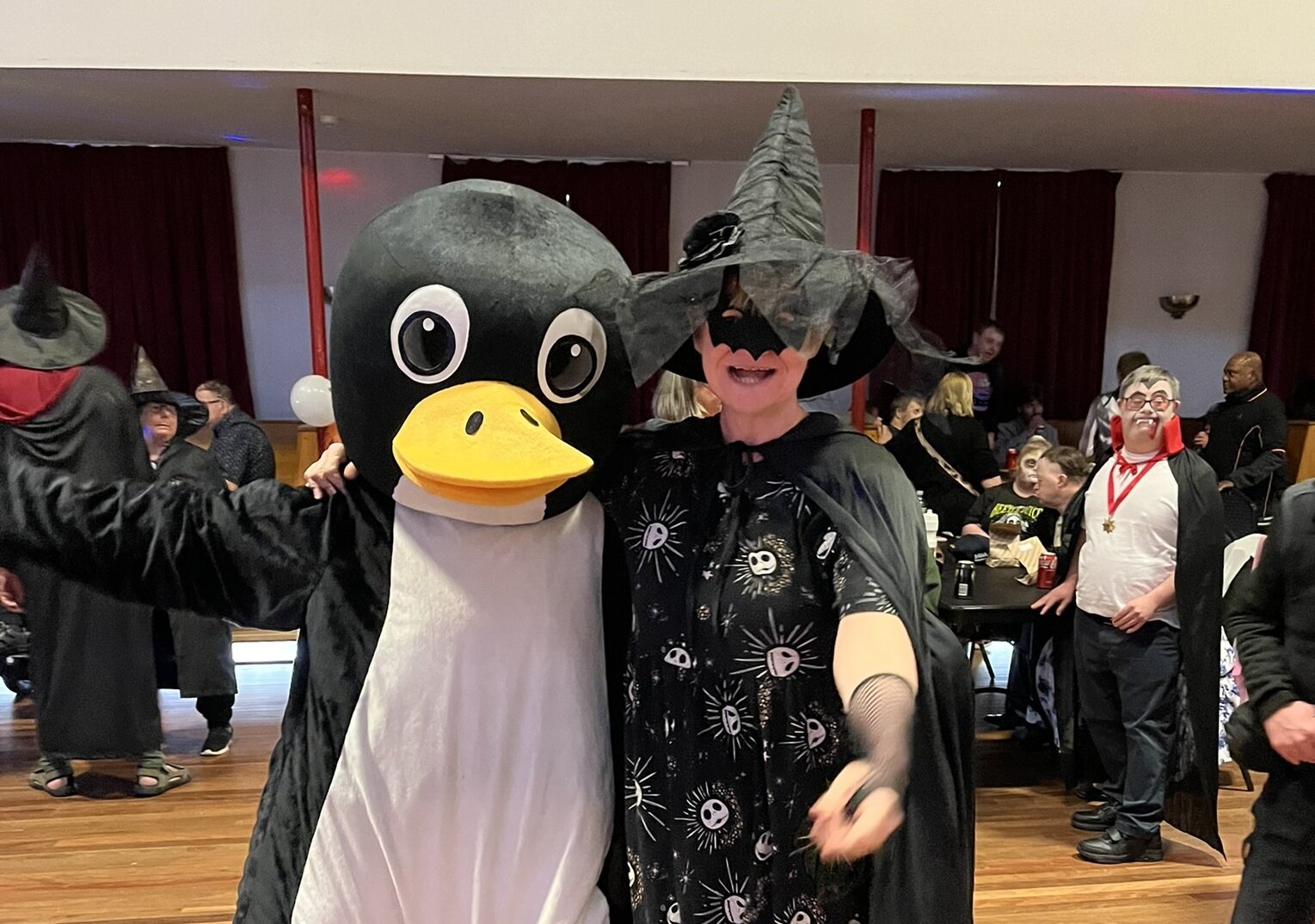 Two people dressed in Halloween costumes, one as a penguin and the other a witch