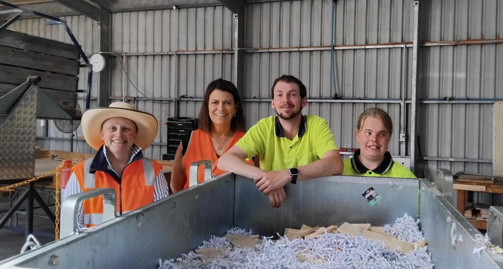 Four people in hi-vis smile for the camera in a warehouse